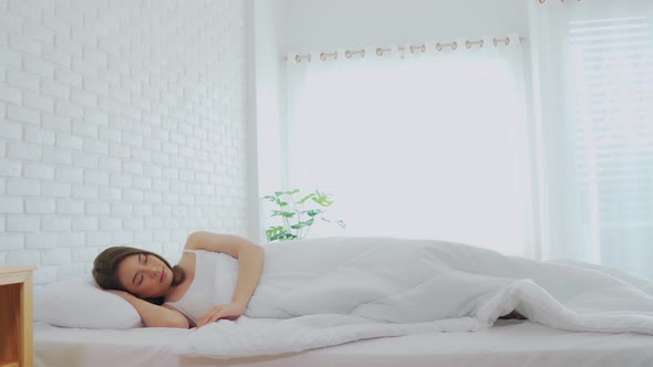 Woman stretching her arm after wake up on bed and looking outside windows
