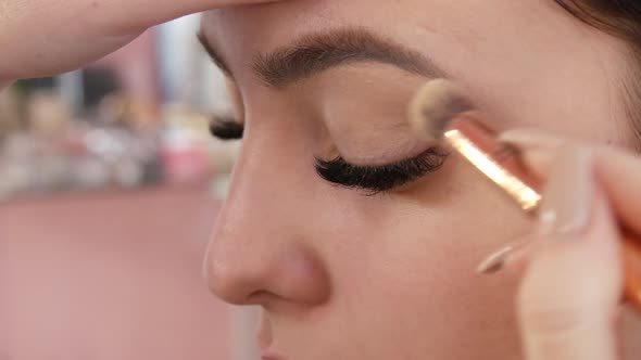A Professional Makeup Artist Applies Grey Eyeshadow with a Special Brush in a Makeup Studio