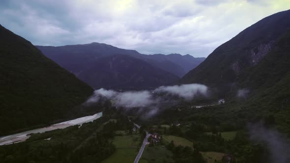 Aerial view of a car driving in a valley with mountains next to the Soca river.