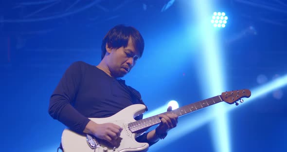 Asian guitar rock star band musician performing in stage in night club with spotlight