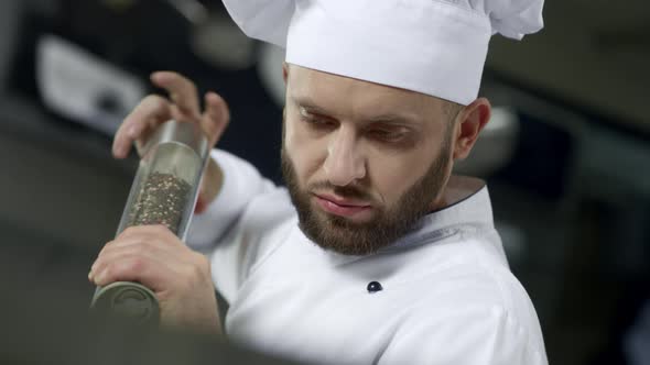 Portrait of Chef Cooking at Kitchen. Closeup Chef Peppering Food in Slow Motion.