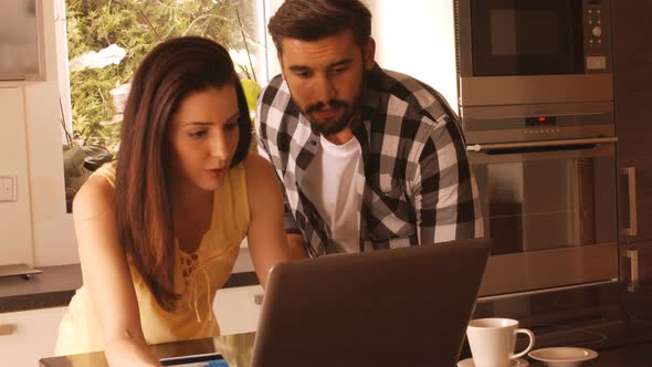 Couple shopping online on laptop using credit card