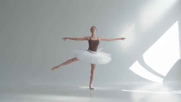 Young Ballerina in Pointe Shoes and White Ballet Tutu Makes Pirouette. Shot on a White Background in