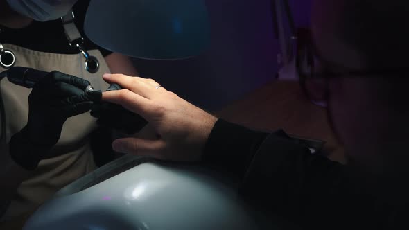 Nail Master Cleans the Nail Out of Cuticle Using a Small Nail Grinder on Male Hands