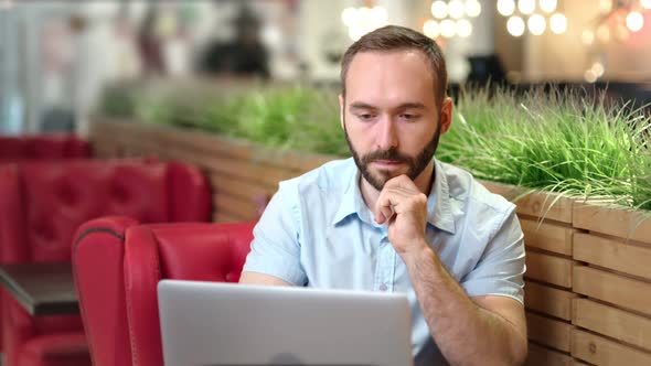 Confident Caucasian Ethnicity Young Man Using Laptop PC at Cozy Coffee Shop or Cafe