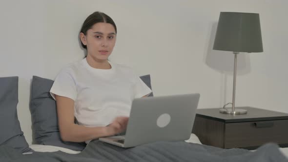 Indian Woman Showing Thumbs Up Sign While using Laptop in Office