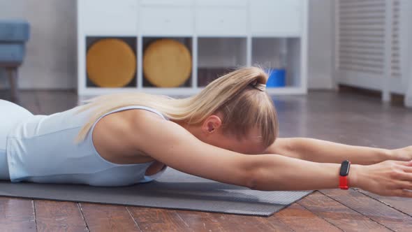 Young and sporty girl in sportswear is using resistance band while doing at home.