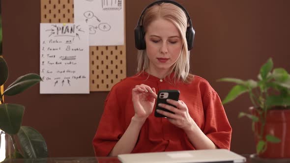 Beautiful blond hair woman in red shirt listen a music at work place