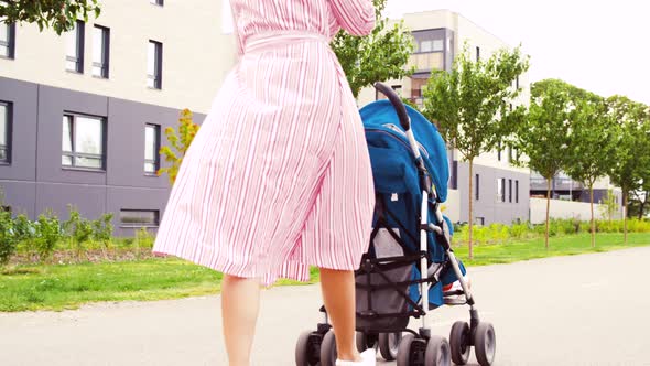 Mother with Stroller Calling on Smartphone in City
