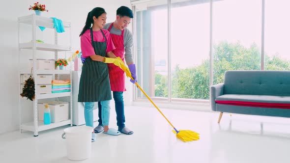 Husband and wife cleaning their room. Happy Asian couple spending time together at home.