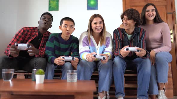 Young multiracial teenagers playing online video game console at home