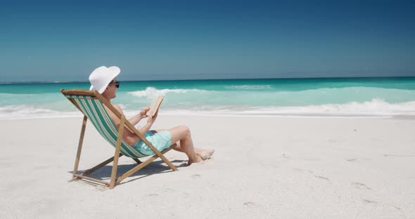 Man reading a book on the beach 