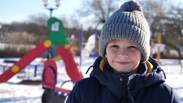 Happy Baby Boy Having Fun with Snow in Winter and Smiling