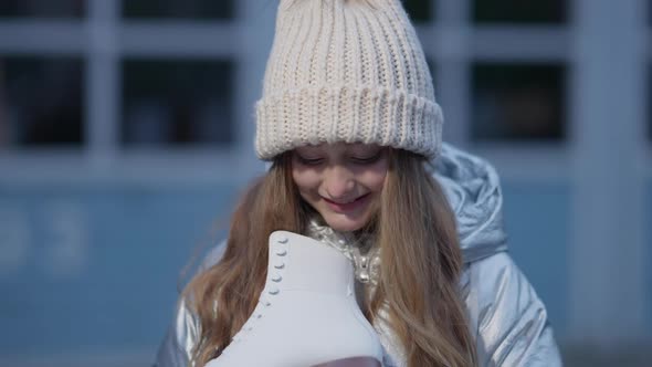 Closeup of Charming Happy Girl Admiring New Ice Skates Standing Outdoors