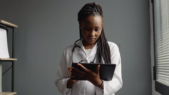 Young African Woman Doctor Works with a Tablet