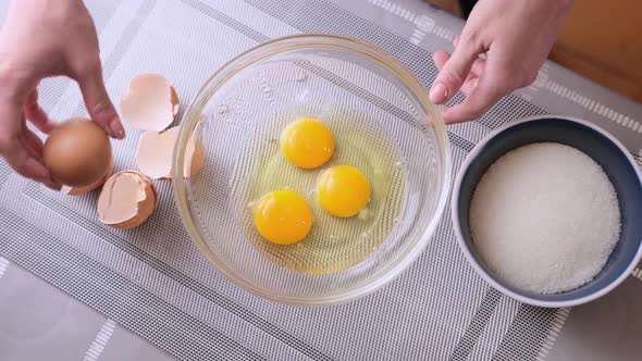 Woman is Crushing Eggs Into Glass Bowl and Making Dough