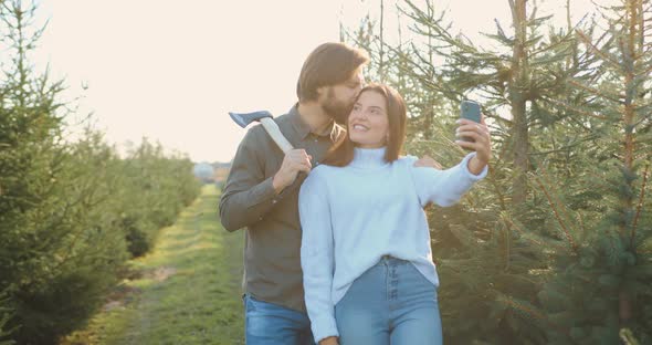 Couple Making Picture when Came in Fir Trees Grove to Cut Down One of the trees for Holidays