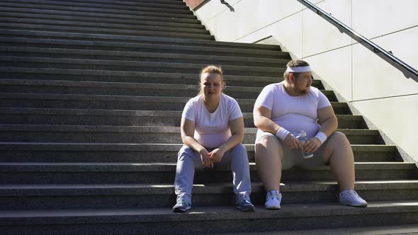 Fat Couple Sitting on Stairs, Exhausted After Physical Trainings, Togetherness
