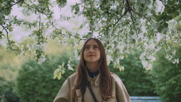 Young woman standing under blooming tree in a park