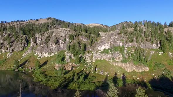 Zooming panorama of a mountain lake then flying towards the dark forest