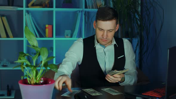 Young Man Counts Money Putting Them in Piles on Table