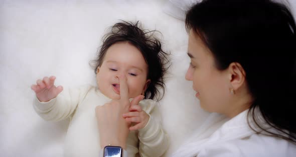 Mother Lying Next to Her Baby Daughter Stroking and Kissing Her