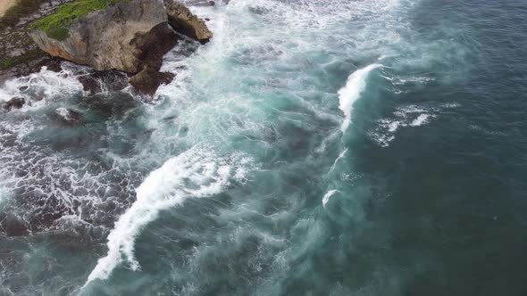 Aerial view of tropical beach in Gunung kidul, Indonesia with green and rocky cliff.