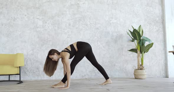 Young Active Slender Girl Wears Black Tracksuit, Practices Yoga Asanas at Home, Exercises in Cozy