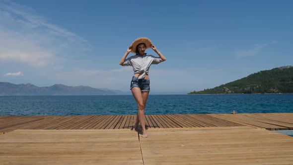 Young Girl in a Hat and Shorts Walking on the Pier