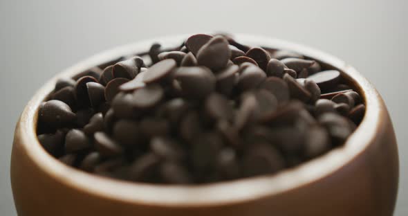 Video of close up of wooden bowl of chocolate chip over grey background