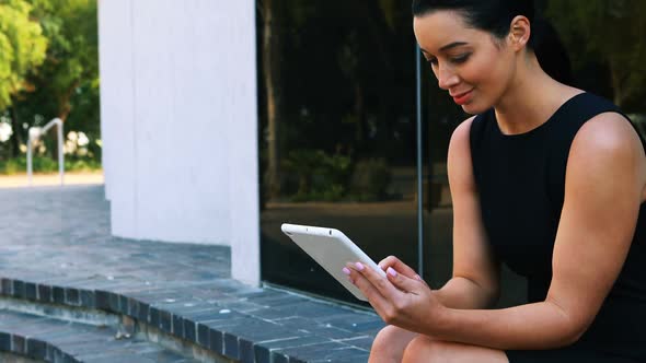 Businesswoman sitting on steps and using digital tablet 4k