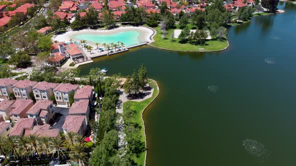 High level aerial fly over of community lake and clubhouse sand lagoon pool