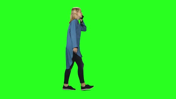 Blonde Teenager Girl Calmly Walking and Talking on the Mobile Phone on Green Screen. Chroma Key