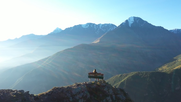 Young Woman Sitting on Bench and Looking at Amazing Mountain View.