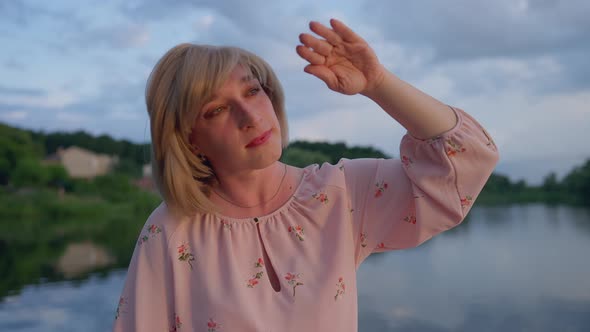 Portrait of Happy Trans Woman Looking at Sun Through Fingers Sitting in Boat on Summer Lake