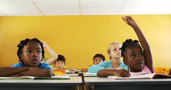 School kids raising hand in classroom