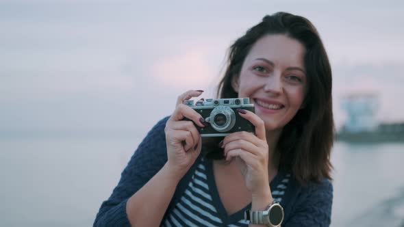 Portrait of a Girl with a Retro Camera. Young Woman Takes Pictures on a Vintage Camera By the Ocean