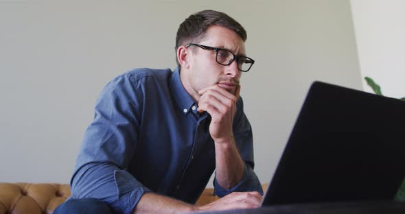 Caucasian man with glasses working from home using laptop