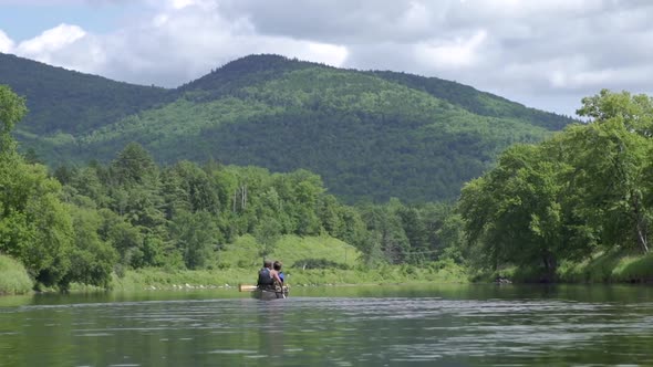 Couple paddling down river in the White Mountains of New Hampshire.