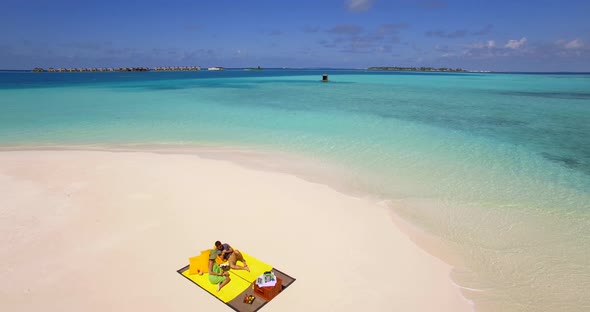 Aerial drone view of a man and woman couple having a picnic meal on a tropical island beach