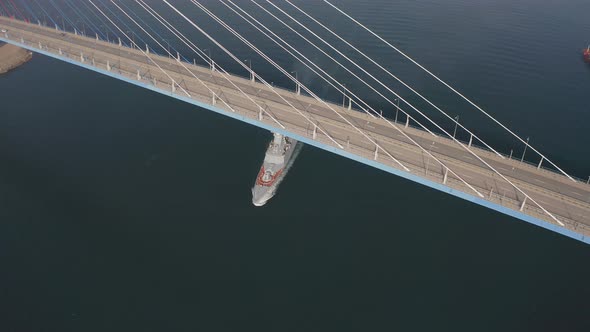 Drone View of a Modern Corvetteclass Ship Going Out to Sea Under the Bridge