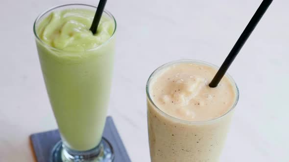 Vegetarian Healthy Smoothies of Raw Avocado and Banana in Glass with Straws