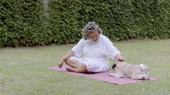 Asian Elderly woman play with dogs in the garden.