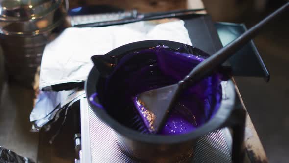 Black bowl full of purple hair dye on table at hair salon