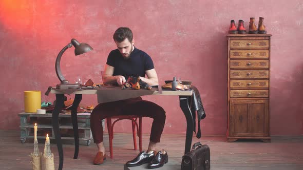 Handsome Man Concentrated on Cutting the Cloth for Shoes