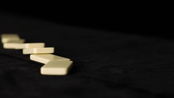 Close up falling white dominoes, domino effect on black background