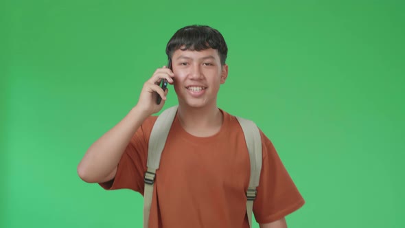 The Front View Of Asian Boy Student Talking On Mobile Phone While Running To School On Green Screen