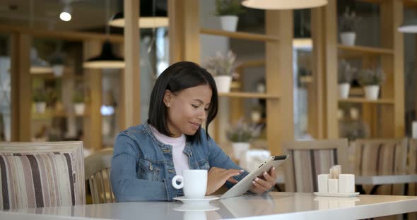 Smiling African Woman Using Digital Tablet at Cafe