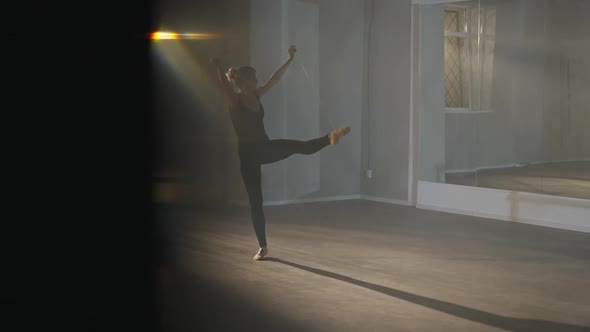 Wide Shot of Slim Adult Ballerina Training in Backlit Fog Indoors
