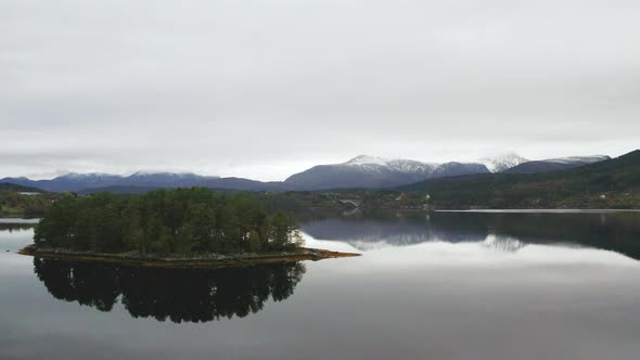 Mirror Reflection On Serene Seascape Surrounded With Hills And Snowcapped Mountains In Norway. Aeria